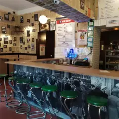 Stylowy bar z zielonymi stołkami i czarno-białą fototapetą. Idealne miejsce, gdzie na drinka w Krakowie.