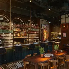 Elegancki bar z mnóstwem butelek alkoholu i kieliszków, idealne miejsce na odkrywanie ciekawych restauracji w Warszawie.