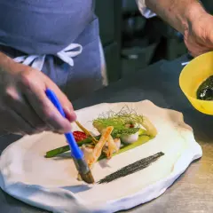 Szef kuchni w restauracji z gwiazdką Michelin precyzyjnie dekoruje danie.