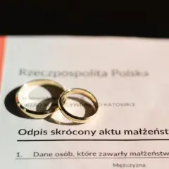 Złote obrączki na odpisie skróconym aktu małżeństwa. Dokument potwierdza zawarcie związku, jak wygląda akt ślubu.