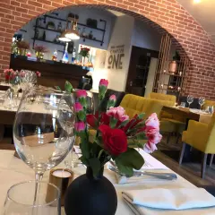 Stolik w jednej z klimatycznych restauracji Lublin. Kwiaty, kieliszki i żółte fotele tworzą przytulną atmosferę.