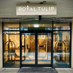 Eleganckie wejście do Royal Tulip Warsaw Apartments z widocznym logo i recepcją.