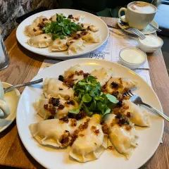 Pyszne pierogi z cebulką i zielenią – idealne pytanie: co zjeść w Poznaniu? Do tego kawa i śmietana.