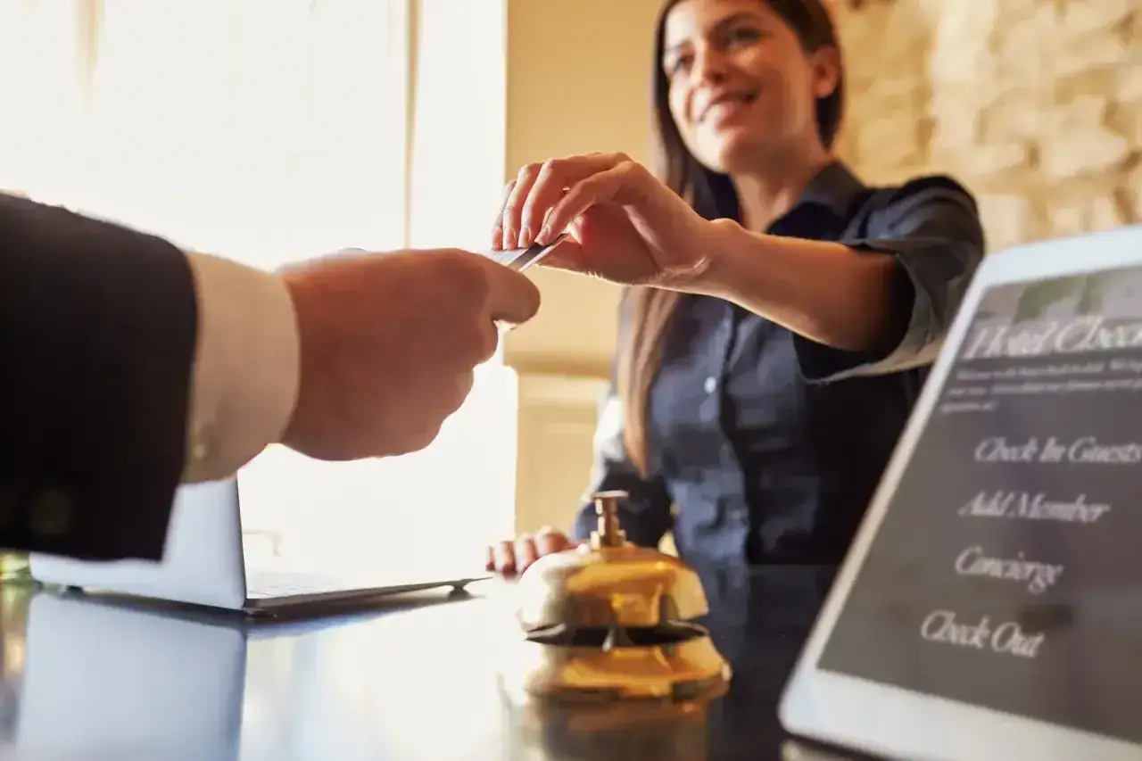Uśmiechnięta recepcjonistka hotelowa przekazuje kartę klienta, kończąc procedurę check out.