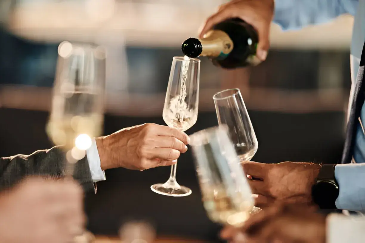 Szampan nalewany do kieliszków. Zastanawiasz się, ile szampana na osobę? To idealny moment na toast!